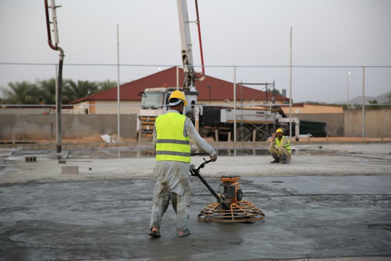 Worker finishing a fresh concrete slab with a power trowel